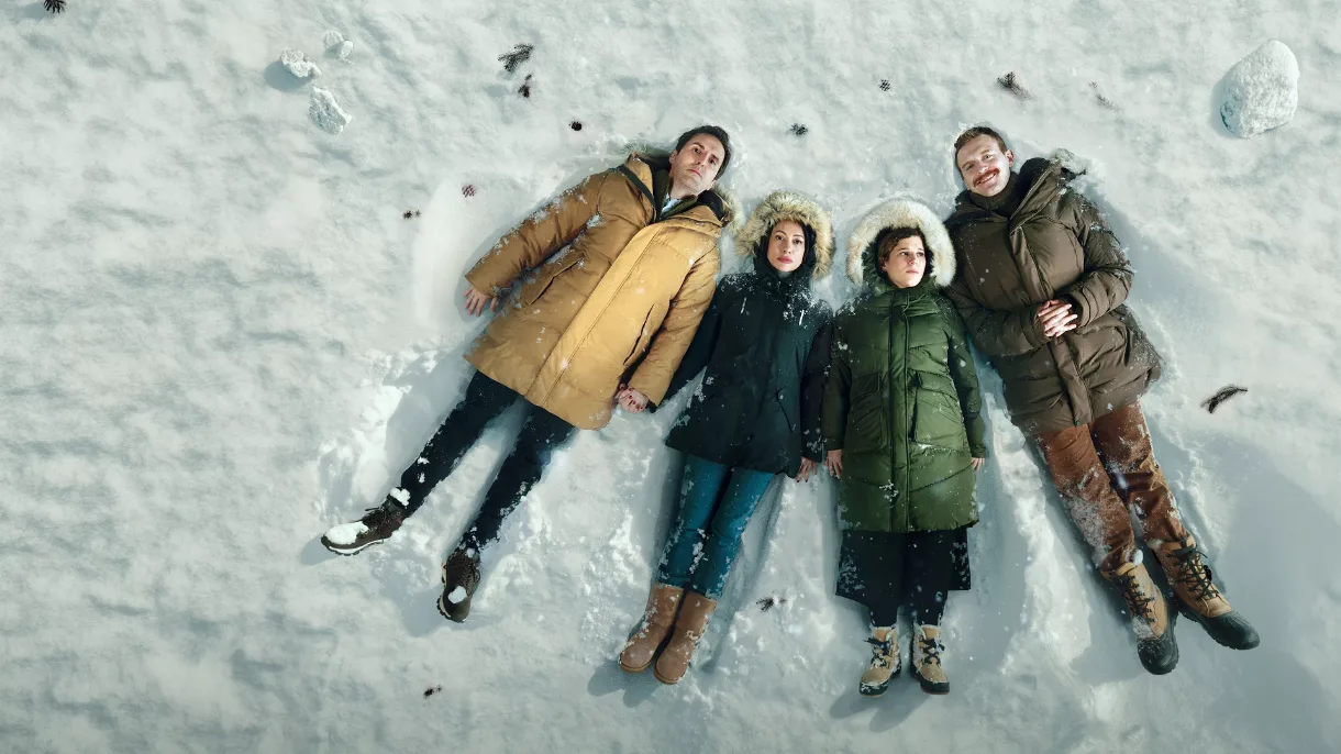 Cuatro amigos tumbados en la nieve